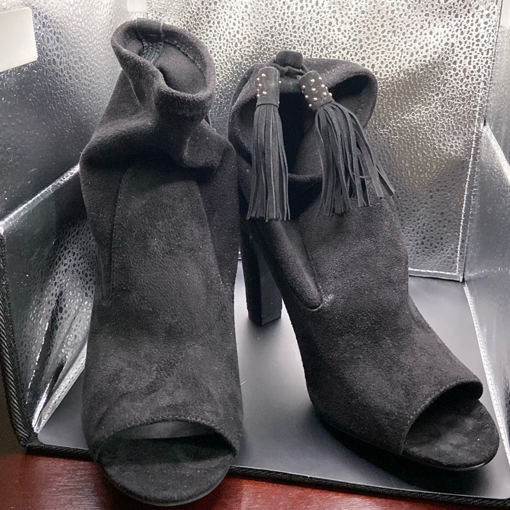 Black suede ankle heel boots with black and white tassel on back and open toe.